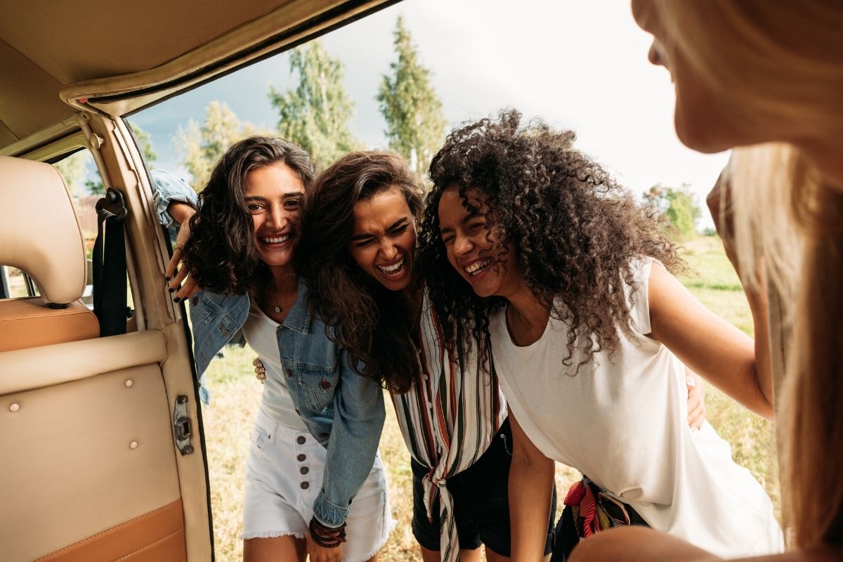 Grupo de amigas sorrindo durante viagem de van